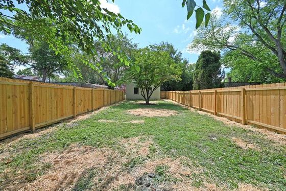 A wooden fence surrounds a large lush green yard.