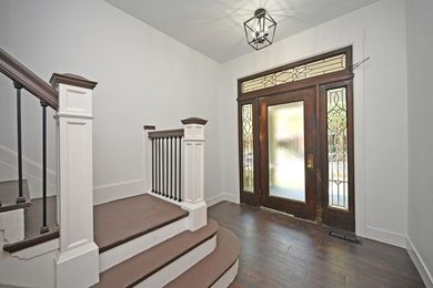 A hallway with stairs leading up to the front door of a house.