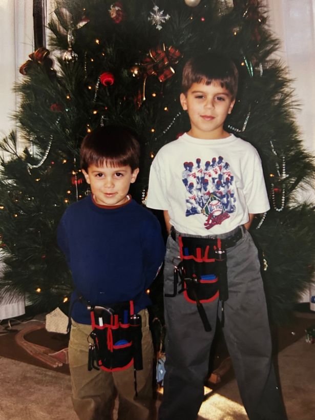 Two young boys standing in front of a christmas tree