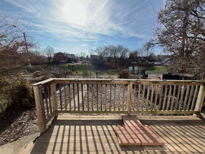 A wooden deck with a view of a river and trees on a sunny day.