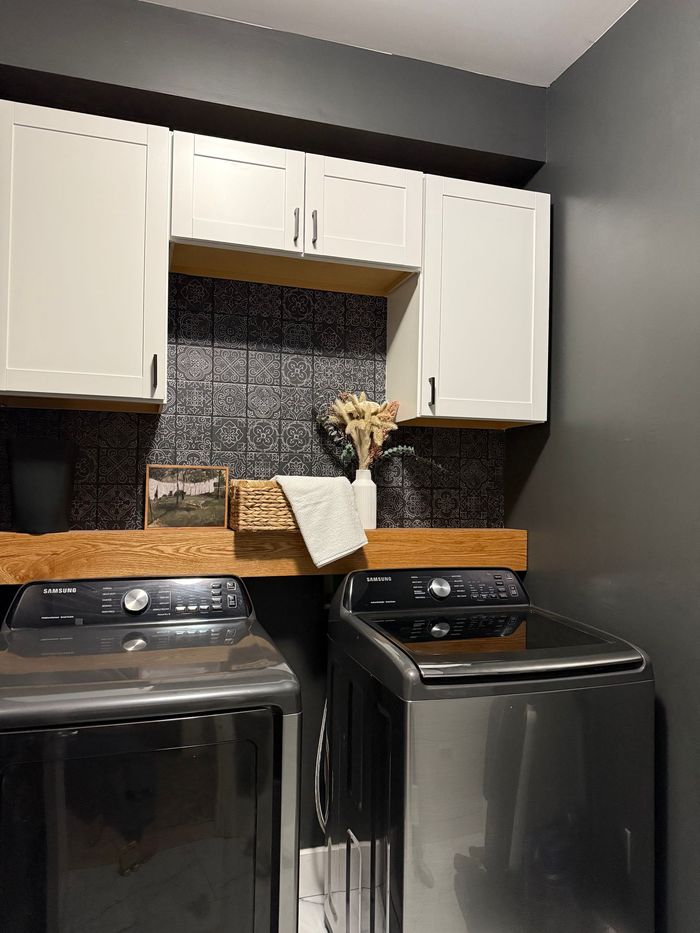 A laundry room with a washer and dryer and white cabinets.