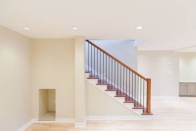 An empty basement with stairs and a wooden railing.