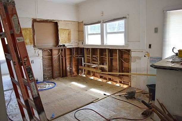 A kitchen under construction with a ladder in the middle of the room.