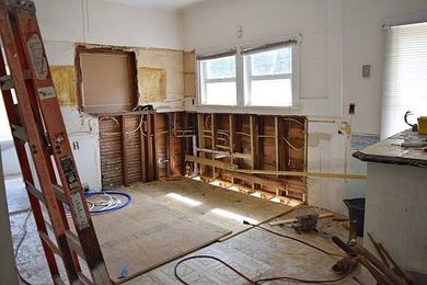 A kitchen under construction with a ladder in the middle of the room.