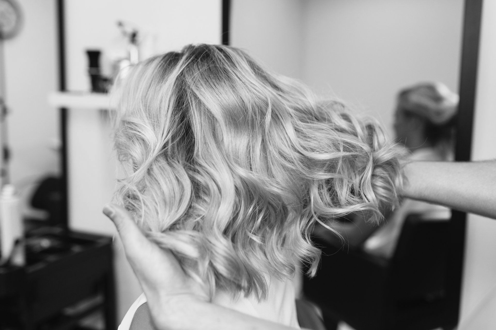 A woman is getting her hair done at a salon in a black and white photo.