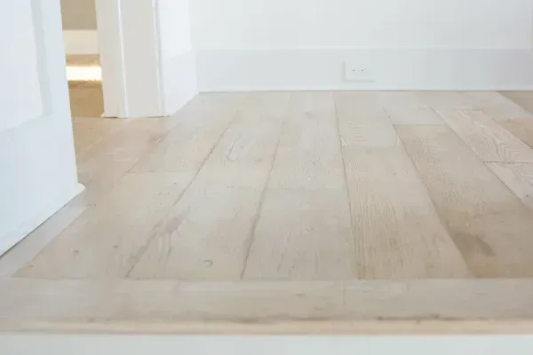A close up of a wooden floor in a room next to a door.
