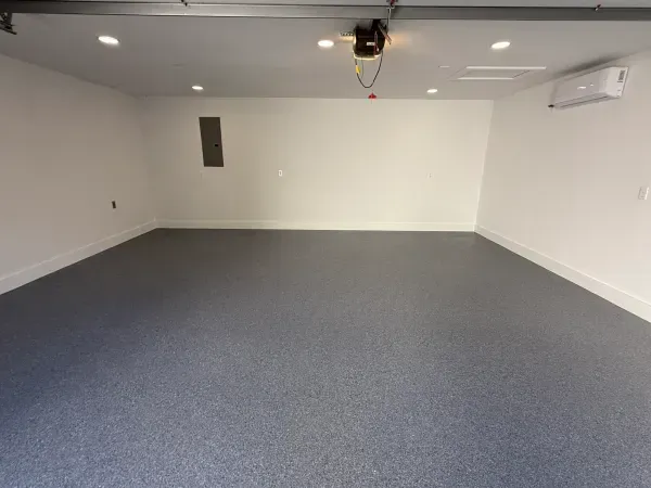 An empty garage with a gray floor and white walls.