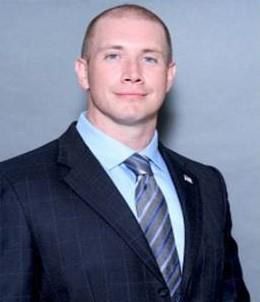 A man in a suit and tie is smiling for the camera.