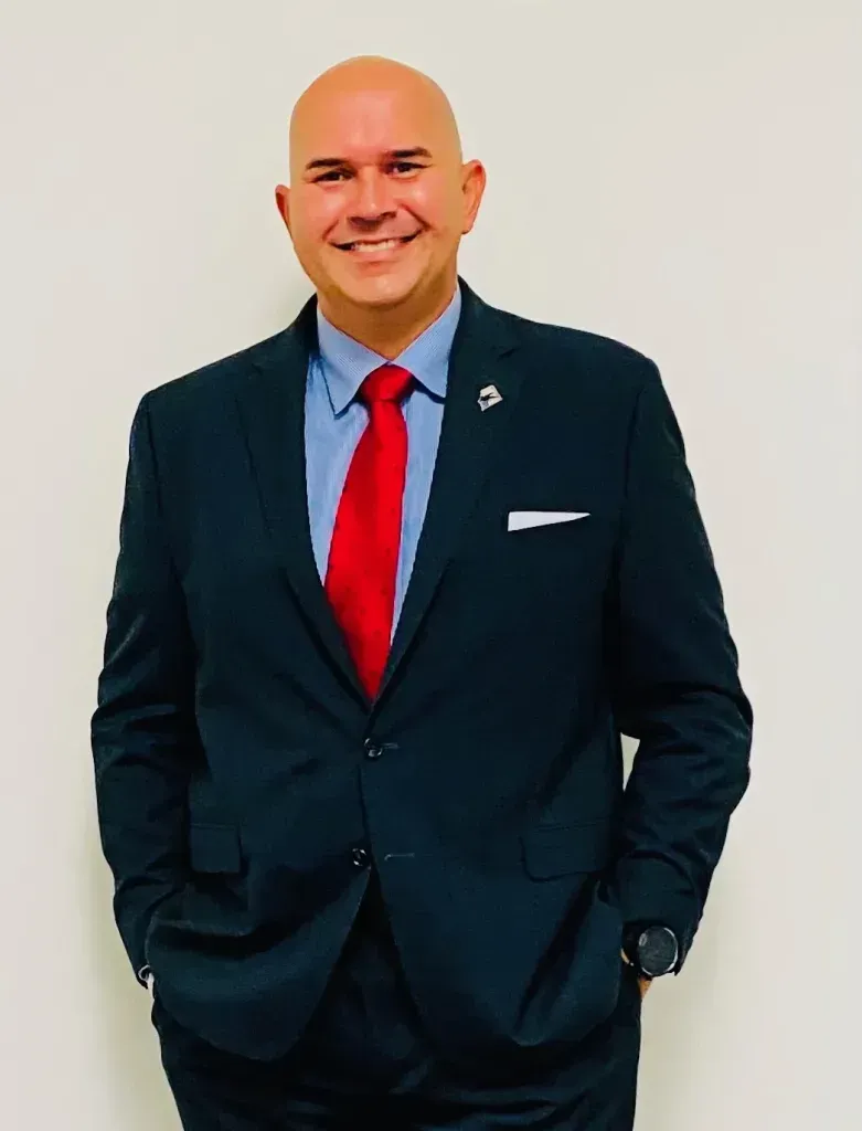 A man in a suit and tie is smiling with his hands in his pockets