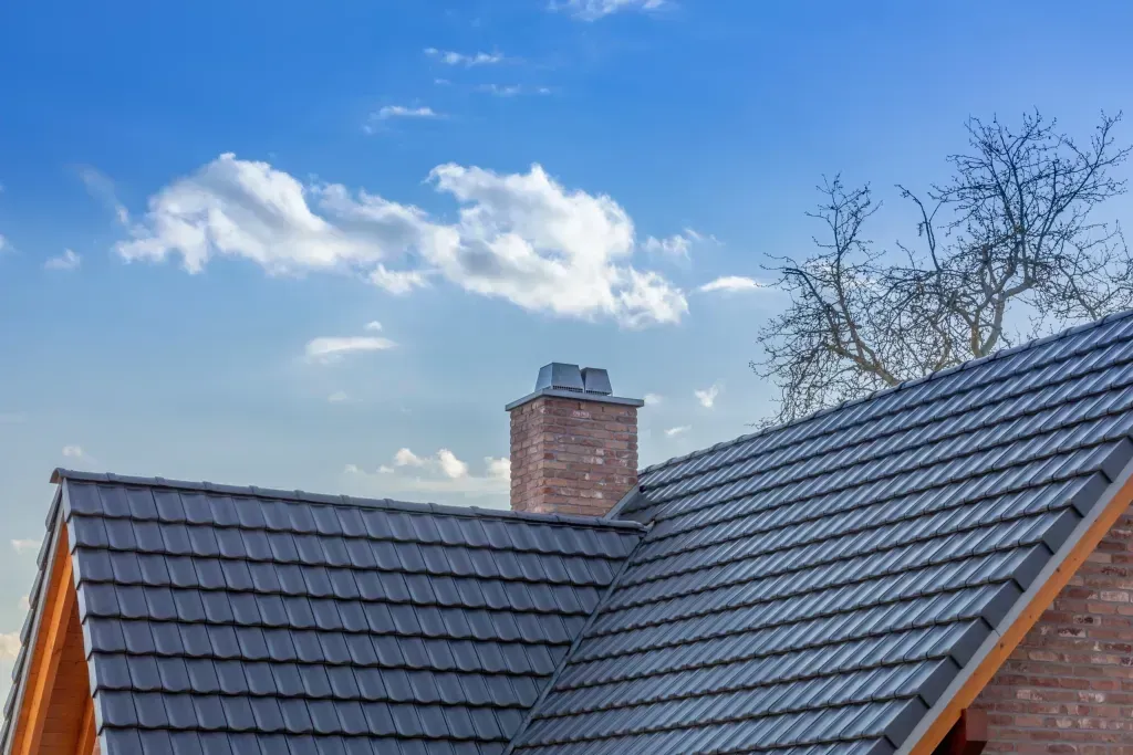 A roof with a chimney on top of it and a blue sky in the background.