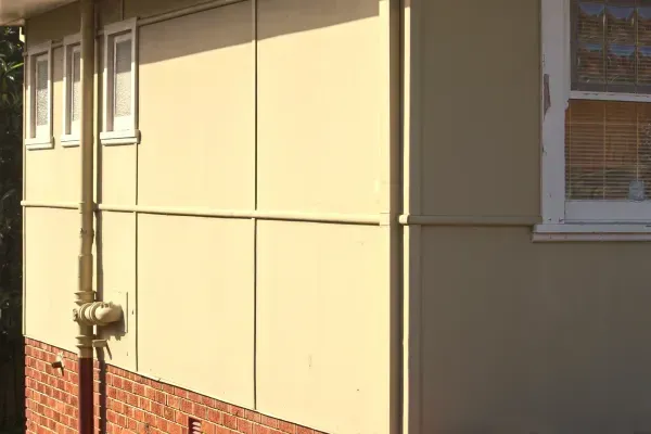 The side of a house with a window and a drain pipe.