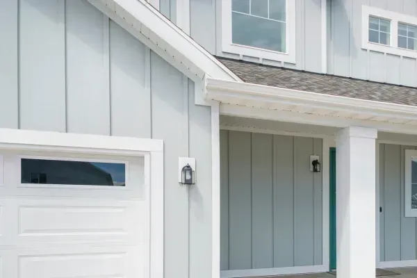 A blue house with a white garage door and a porch.