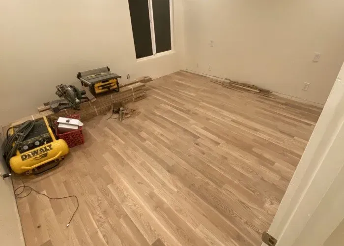 A room with hardwood floors and a dewalt air compressor on the floor.