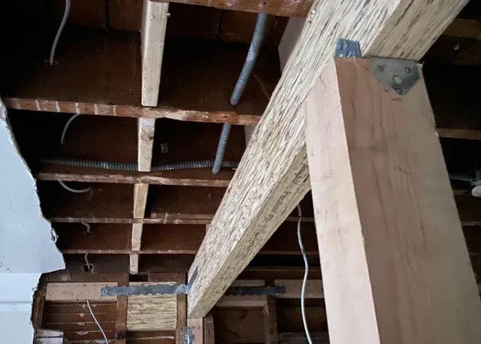 A ceiling with a lot of wooden beams and wires hanging from it