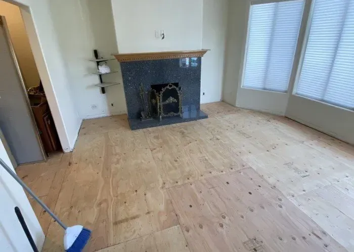 A living room with a fireplace and a broom on the floor.