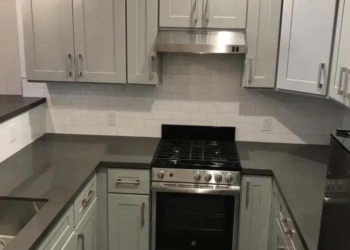 A kitchen with a stove , oven , sink , and cabinets.