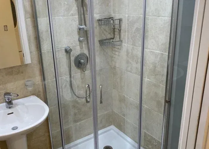 Small bathroom with a pedestal sink and a glass shower enclosure.