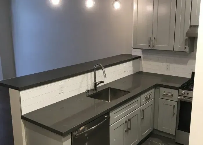 A kitchen with a sink , stove , dishwasher and cabinets.