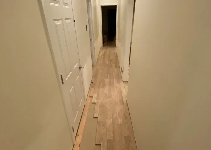 A long hallway with hardwood floors and white doors.