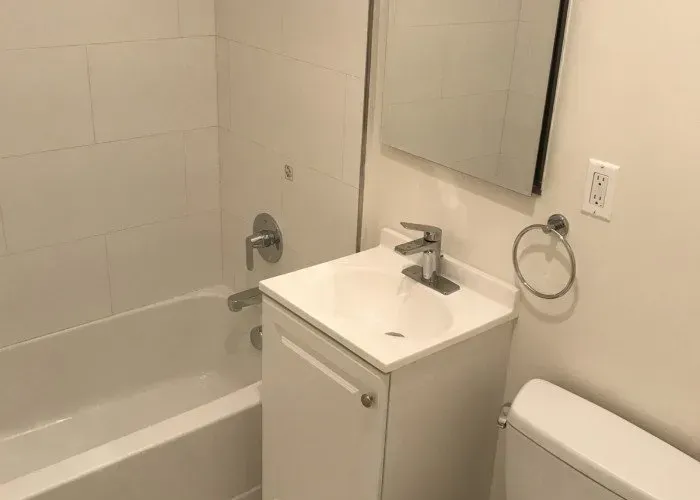 A bathroom with a sink , toilet , tub and mirror.