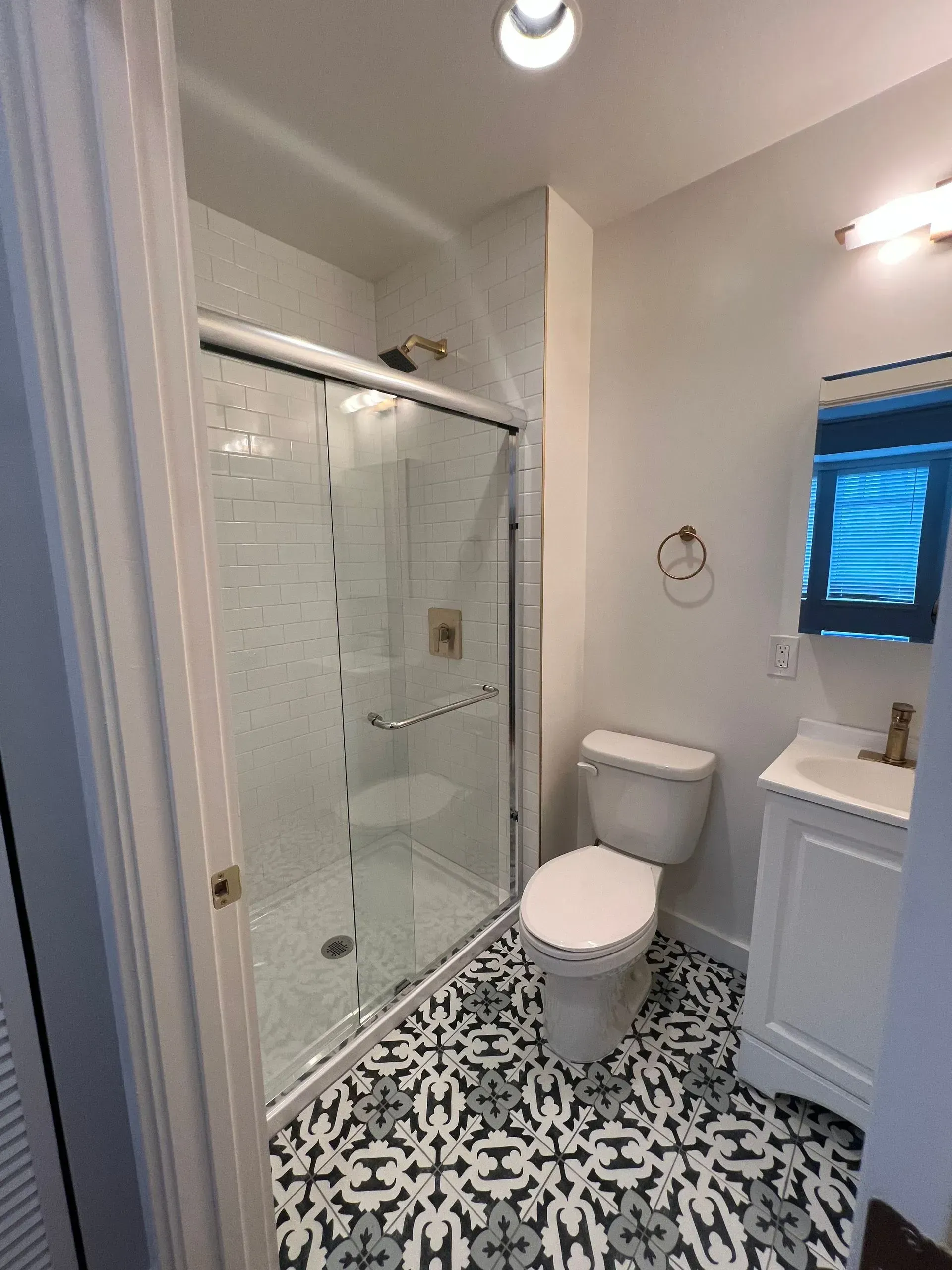 A bathroom with a toilet , sink and shower.