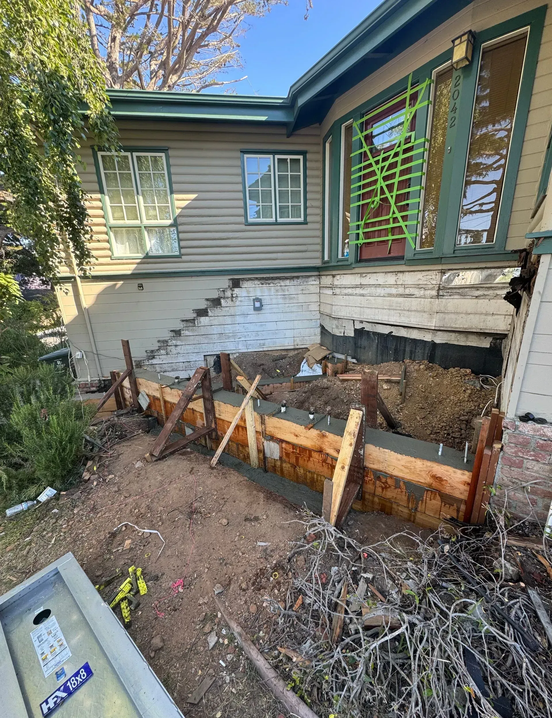 Exterior view of house with wooden forms for concrete work in foreground.