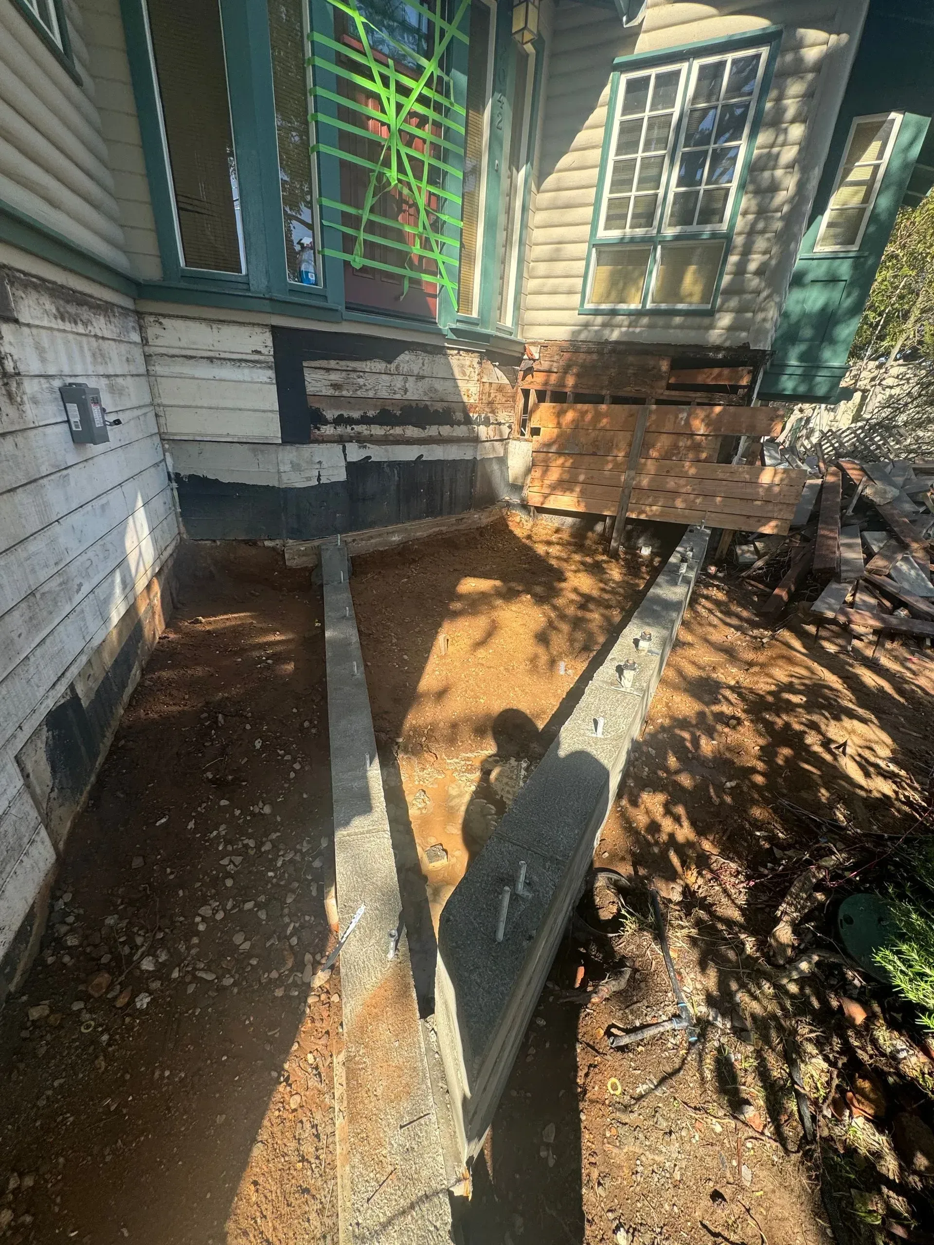 A house is being demolished and a concrete walkway is being built in front of it.