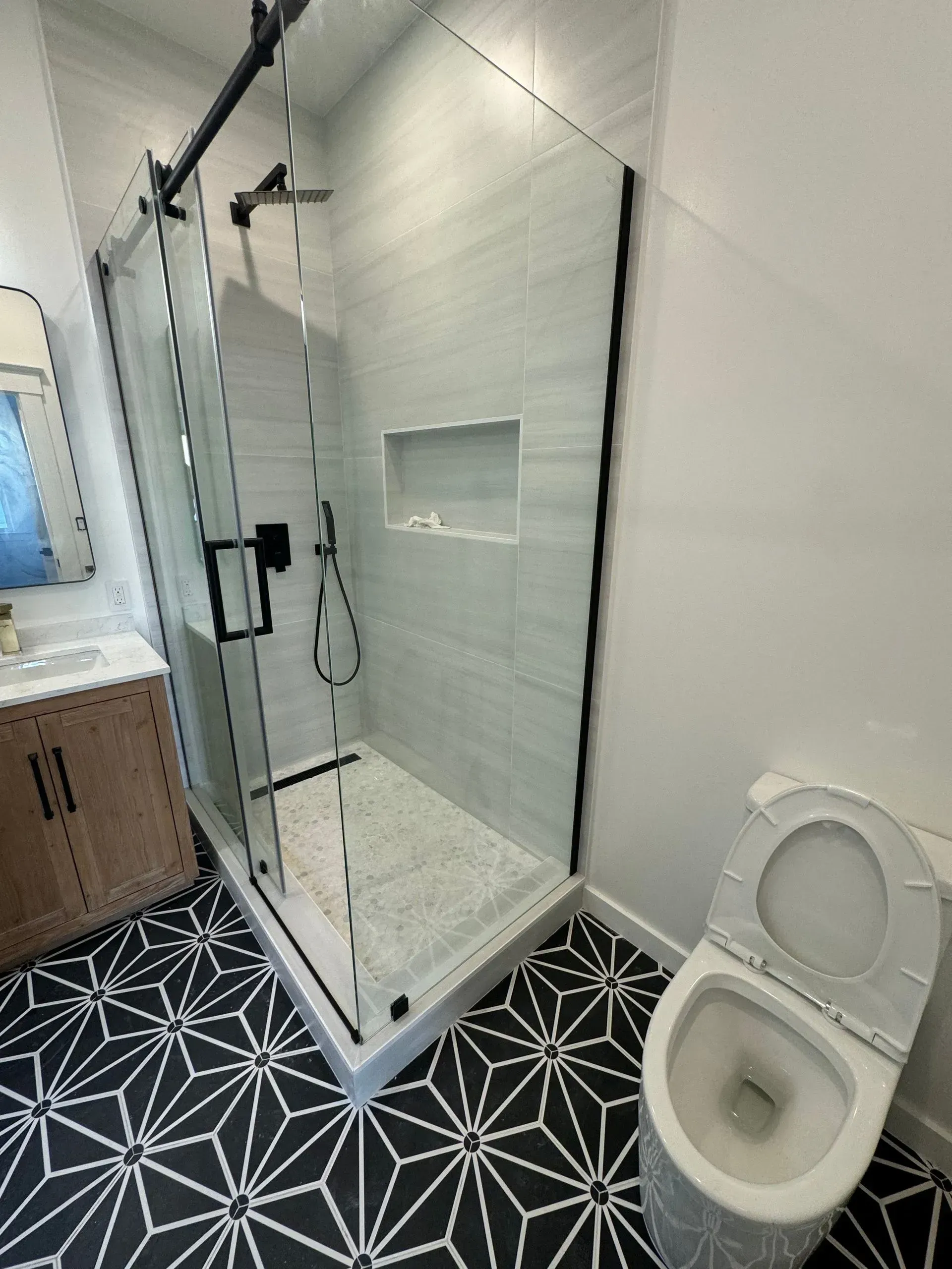 A bathroom with a toilet , shower , sink and mirror.