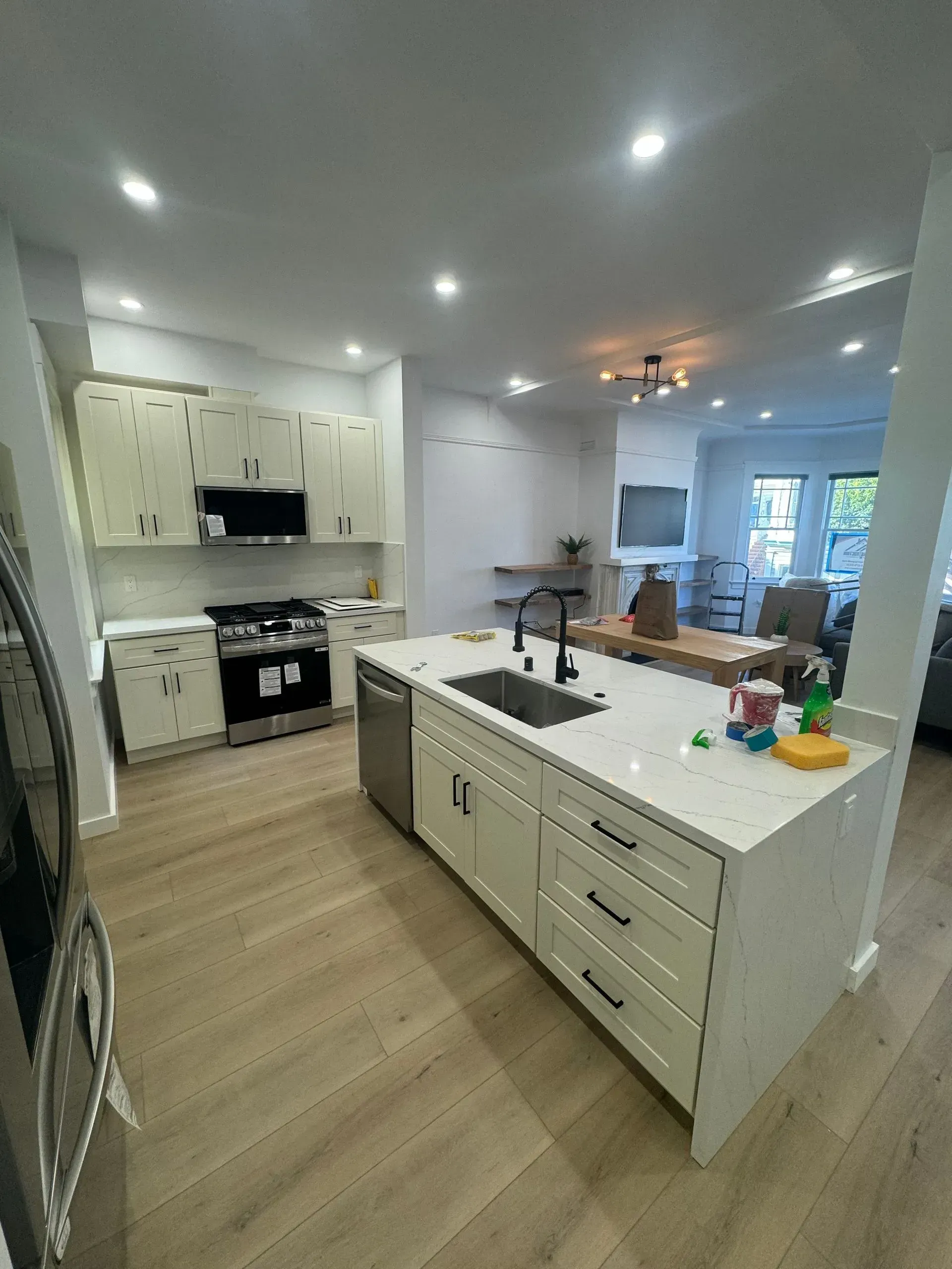A kitchen with white cabinets , stainless steel appliances , and a large island.