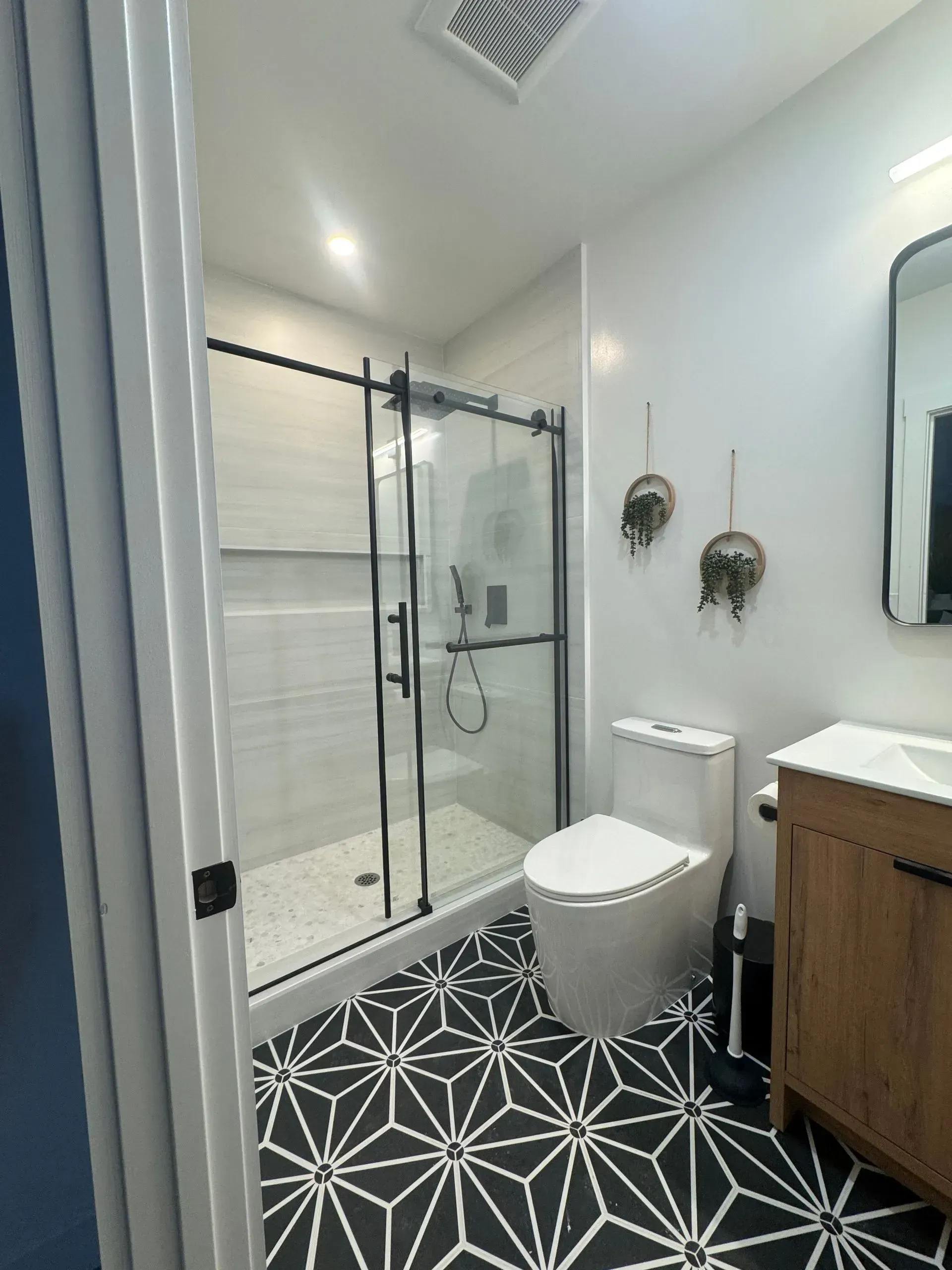 A bathroom with a toilet , sink , shower and mirror.