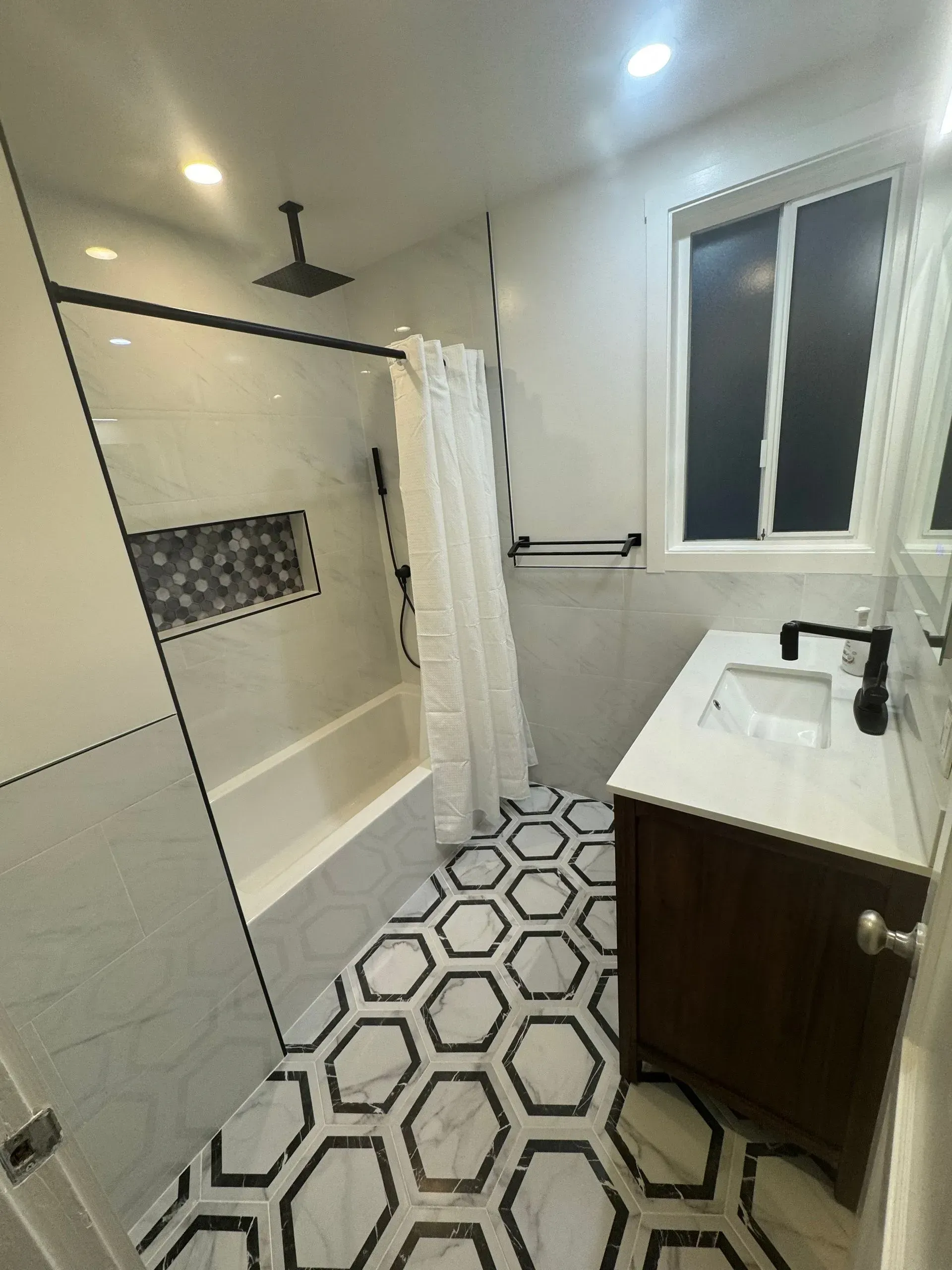 A bathroom with a sink , tub , shower and window.