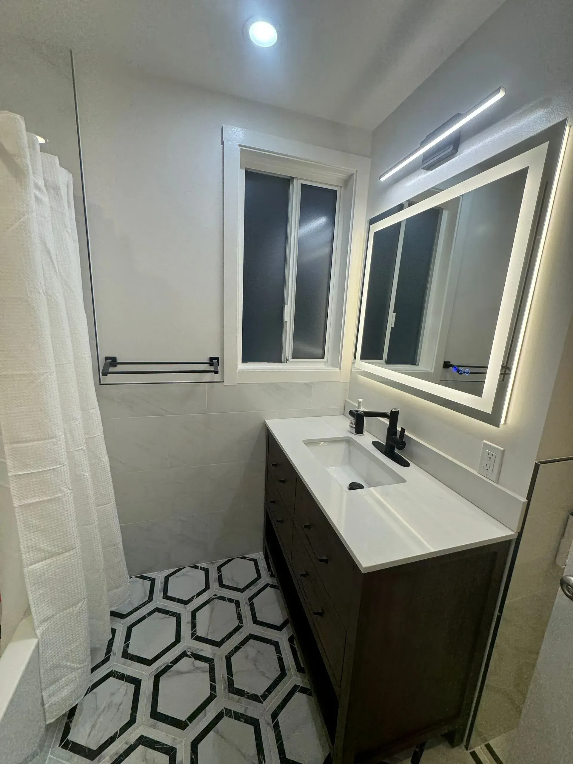 A bathroom with a sink , mirror and shower curtain.