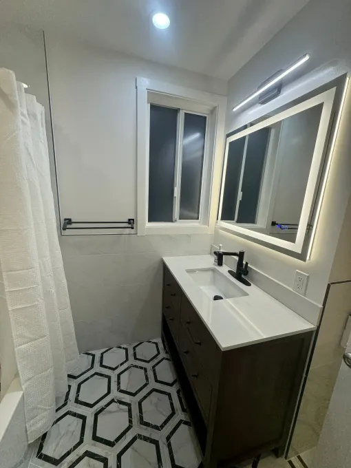 A bathroom with a sink , mirror and shower curtain.