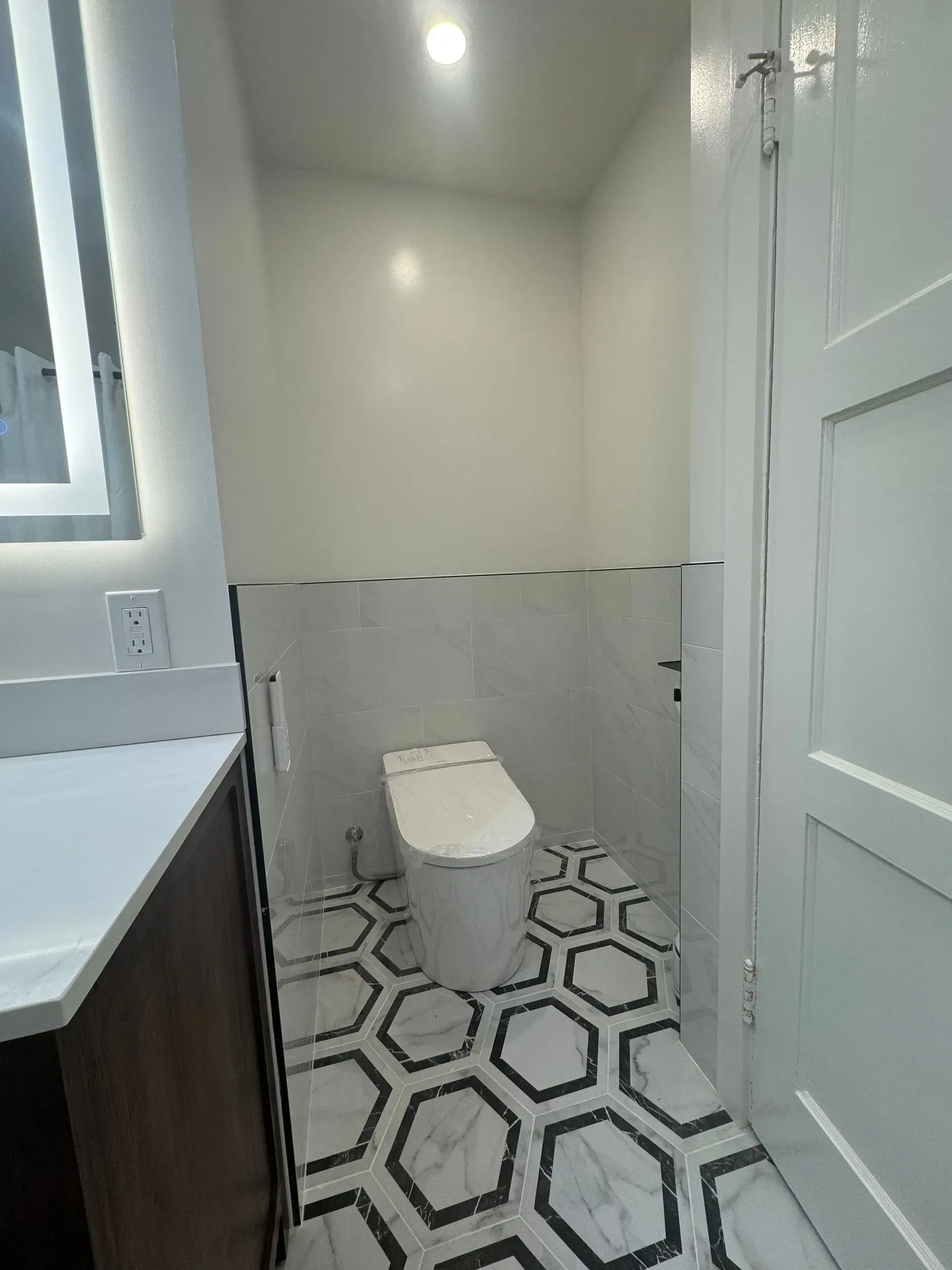 A bathroom with a toilet , sink and mirror.