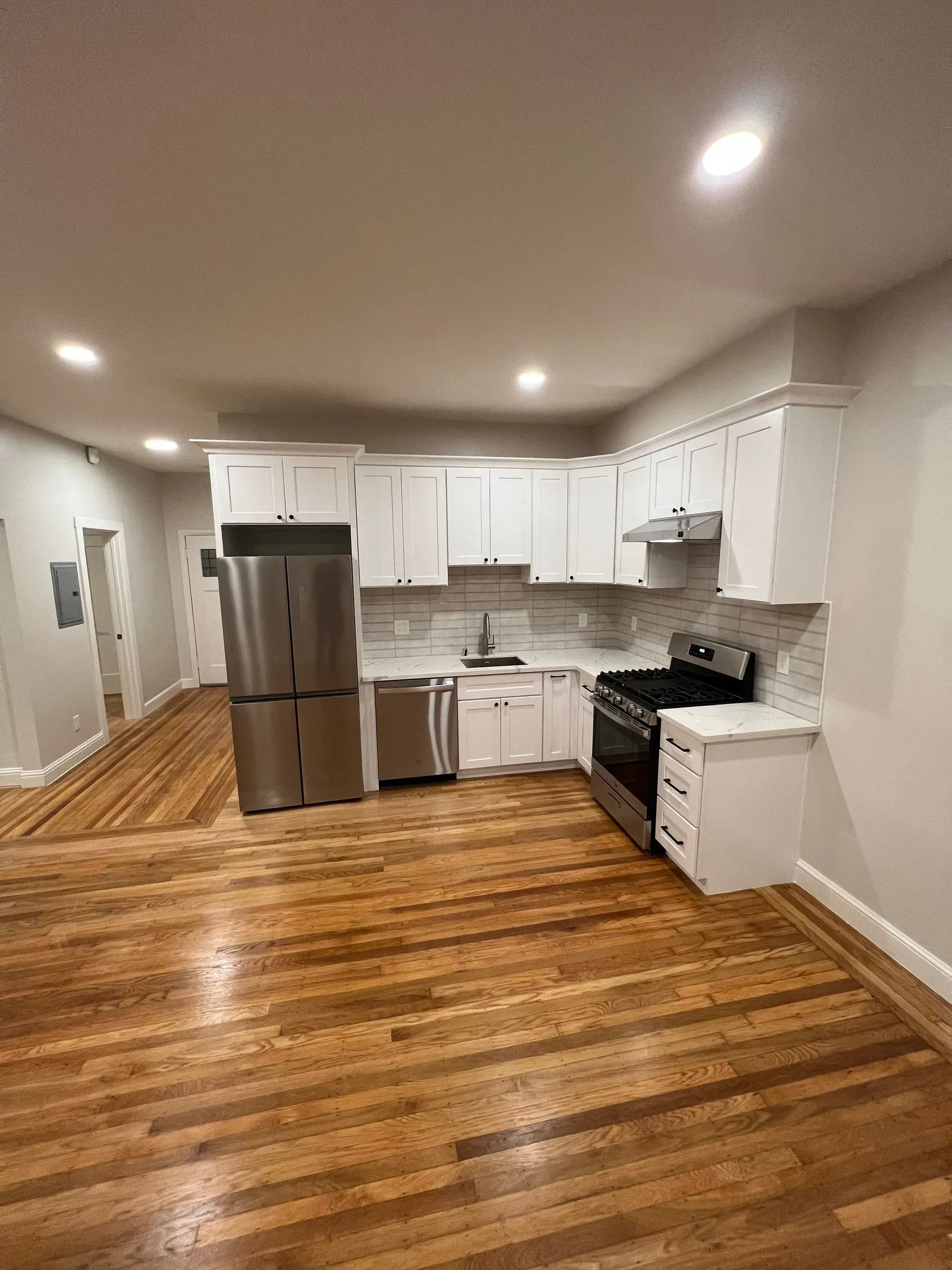 A kitchen with white cabinets , stainless steel appliances , and hardwood floors.
