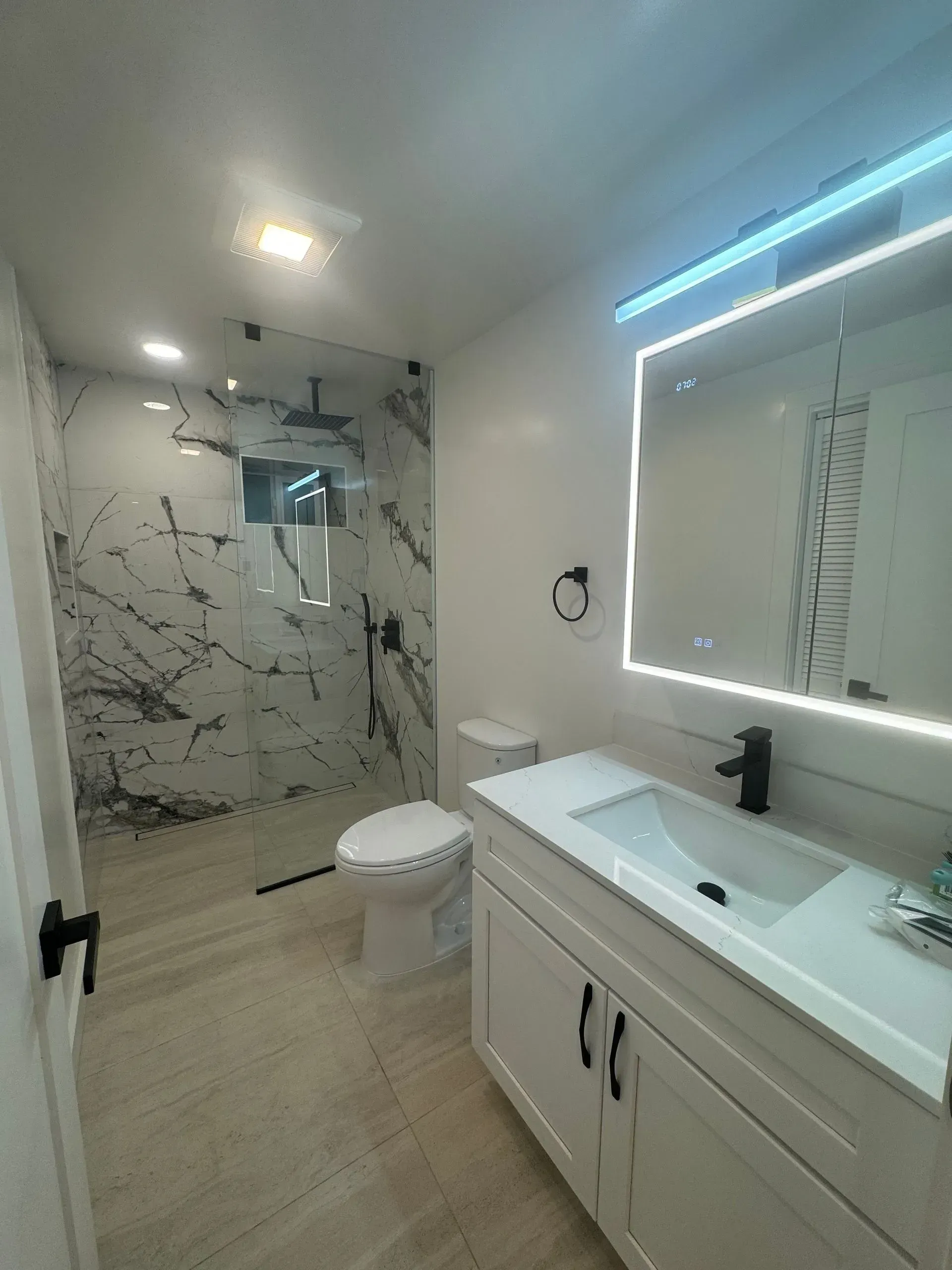 A bathroom with a sink , toilet , shower and mirror.