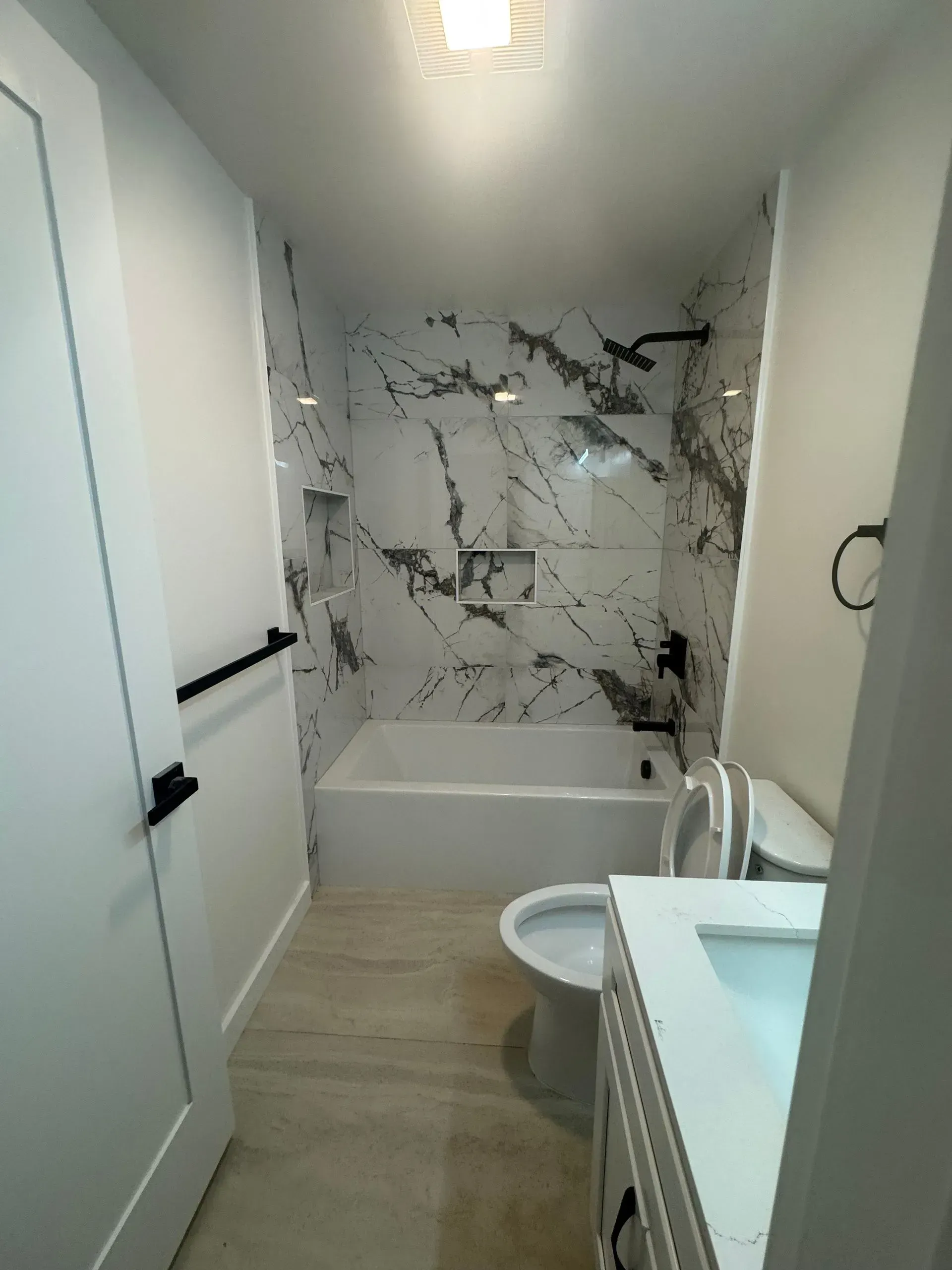 A bathroom with a tub , toilet , sink and shower.