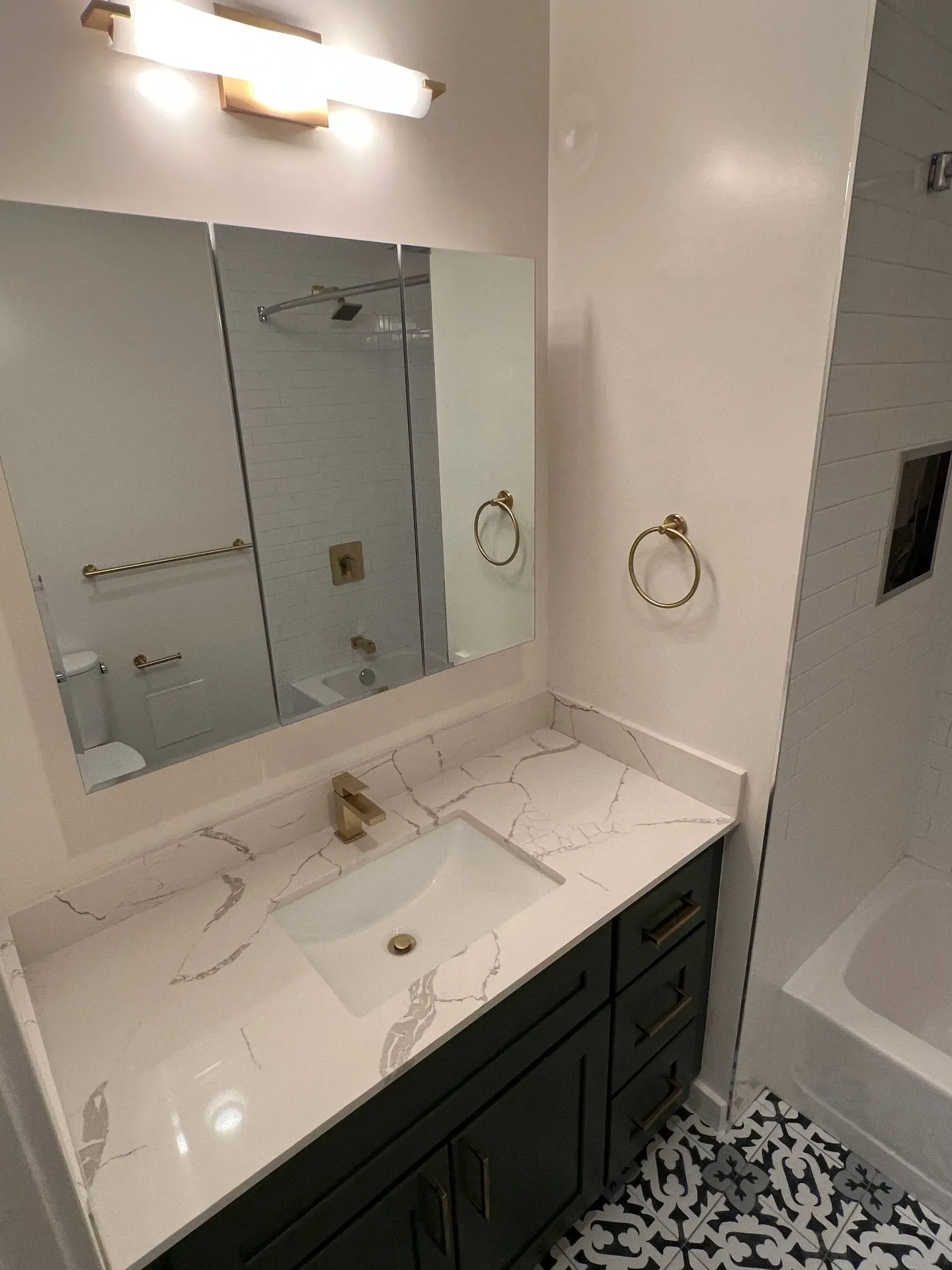 A bathroom with a sink , mirror and bathtub.