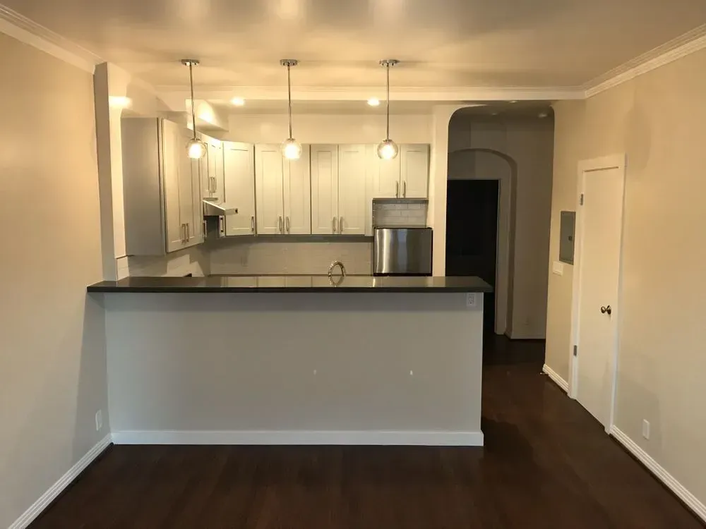 A kitchen with white cabinets and a stainless steel refrigerator