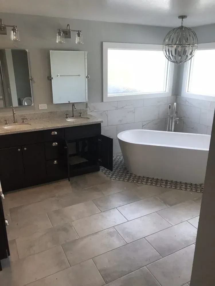 A bathroom with a tub , sinks , mirrors and a window.