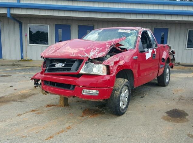 Red Ford pickup truck damaged in a collision; front end crumpled, windshield shattered.