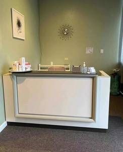A white reception desk in a room with a clock on the wall