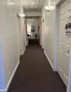 A long hallway with brown carpet and white walls in a building