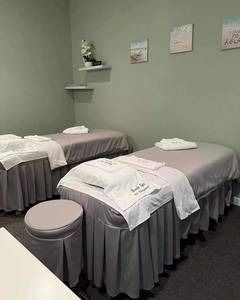 A room with two massage beds and two ottomans in it