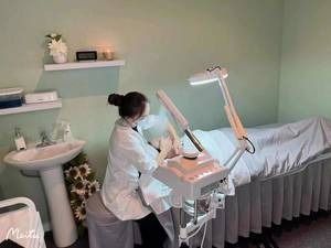 A woman is sitting on a stool in a room using a machine