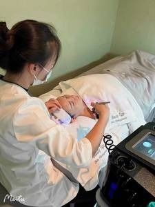 A woman is laying on a bed getting a facial treatment
