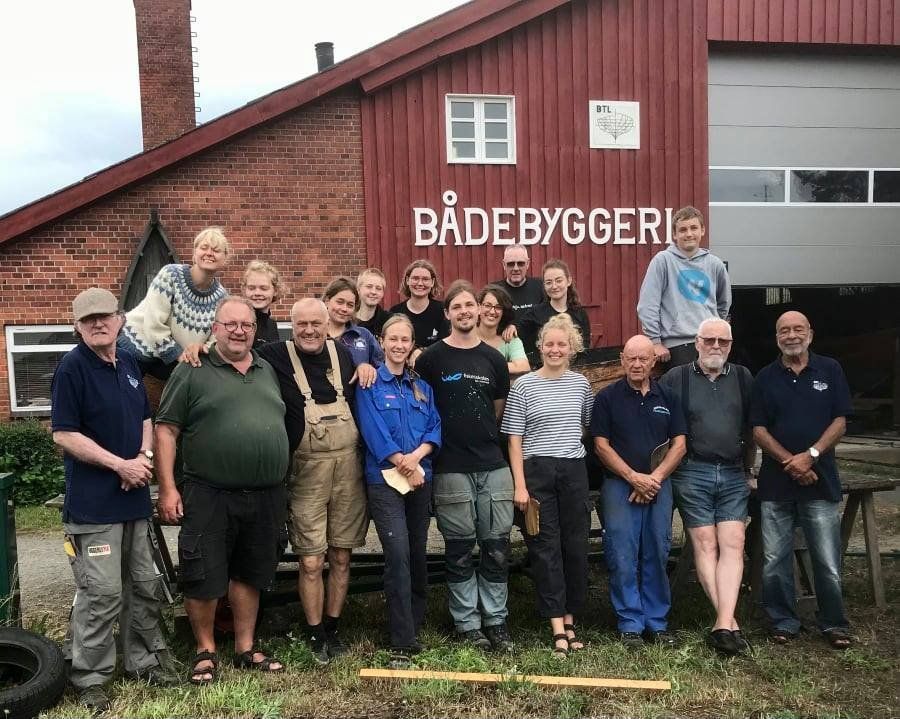 A group of people posing for a picture in front of a building that says badebyggeri
