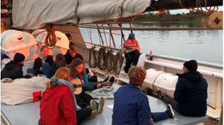 A group of people are sitting on a boat playing guitars.