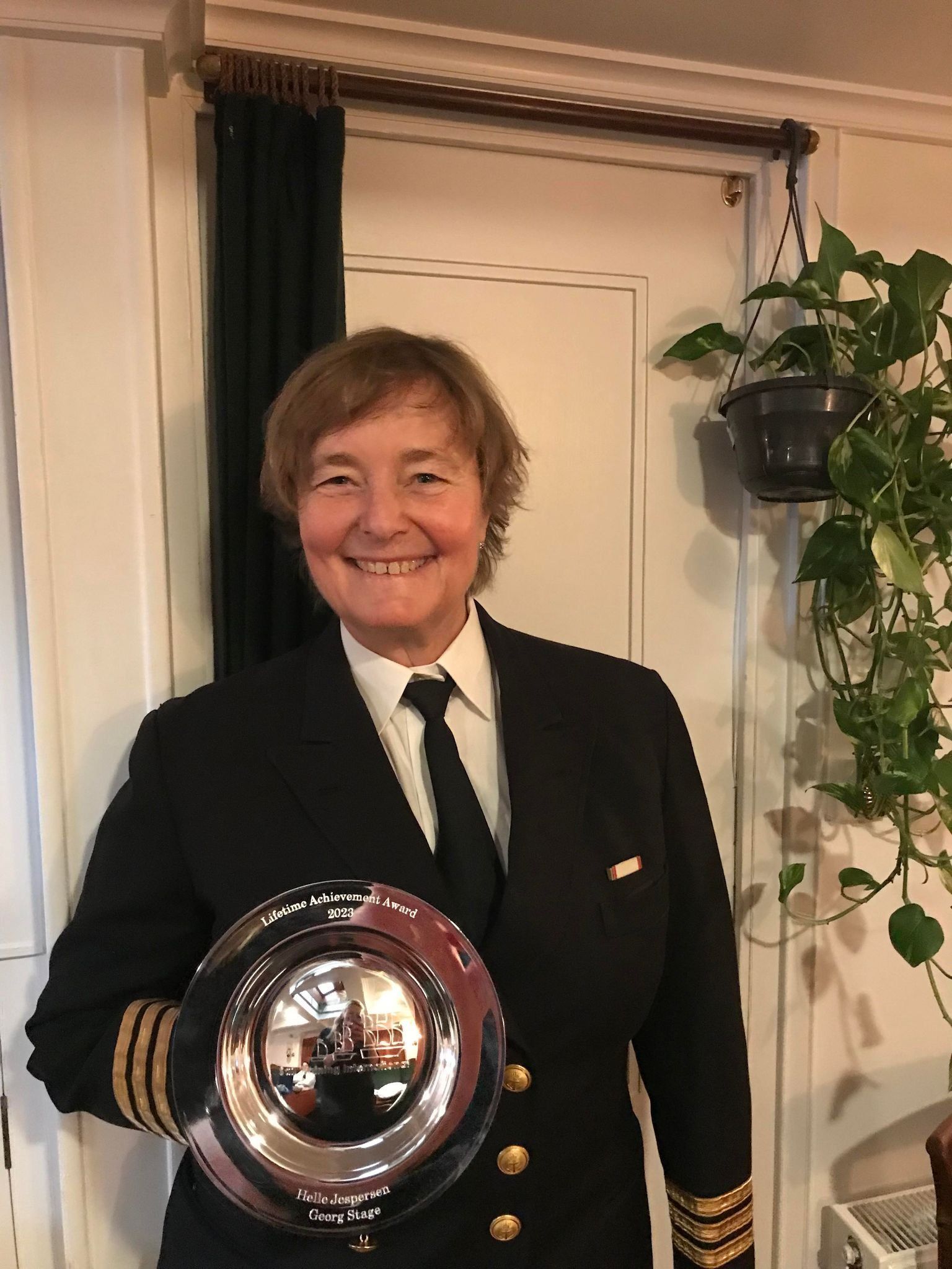 A woman in a suit and tie is holding a trophy.