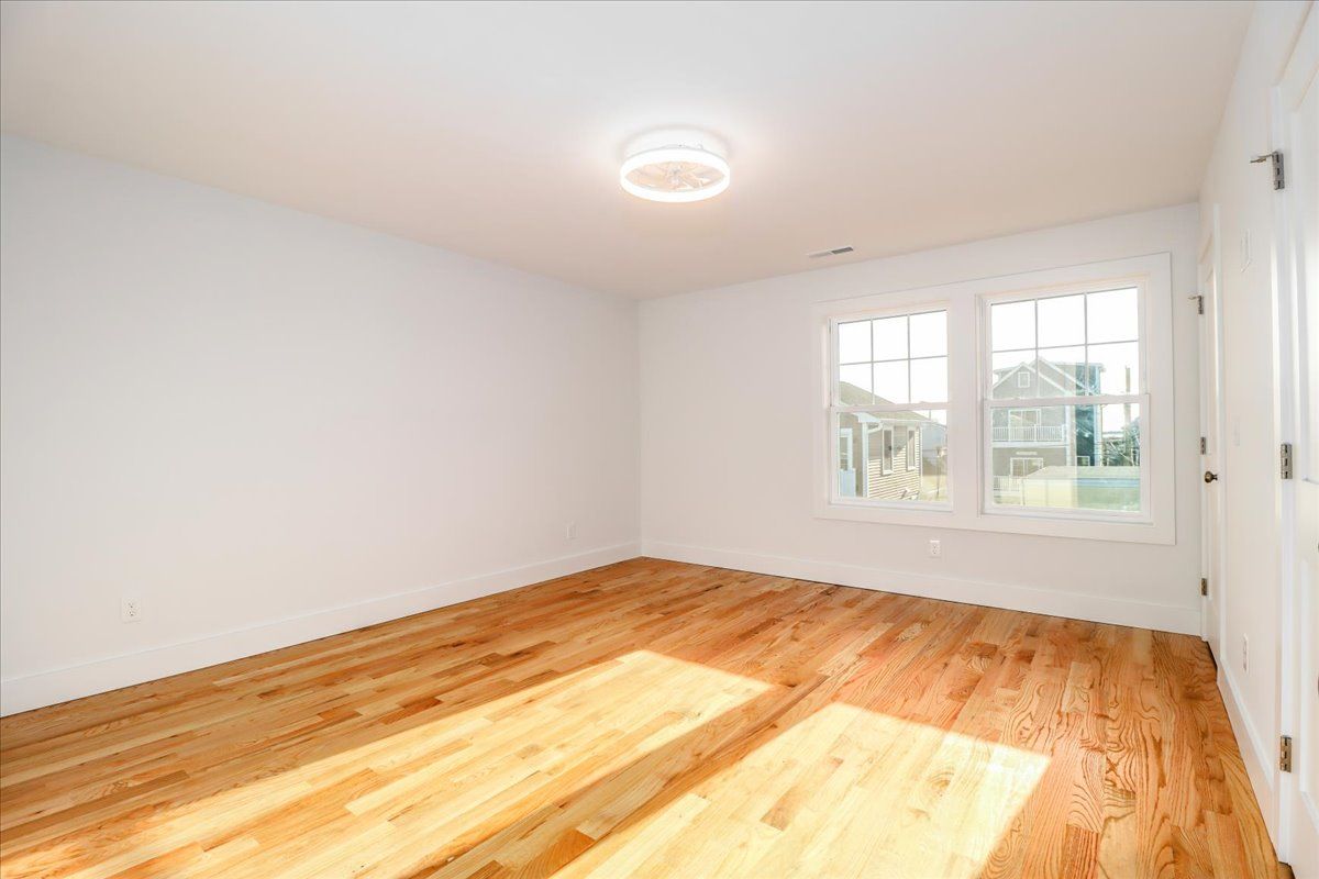 Empty room with wood floors, white walls, and a window.